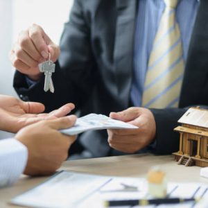 Real Estate Negotiation. The real estate agent or seller receives money and gives the customer the house keys after the purchase agreement is reached.